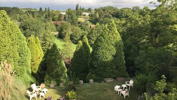 Ein üppiger Garten mit ordentlich geschnittenen Hecken, einem Rasen und Sitzgelegenheiten im Freien.