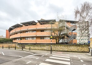 Ein mehrstöckiges Gebäude mit einer geschwungenen Fassade, einer Treppe und einer Backsteinmauer.