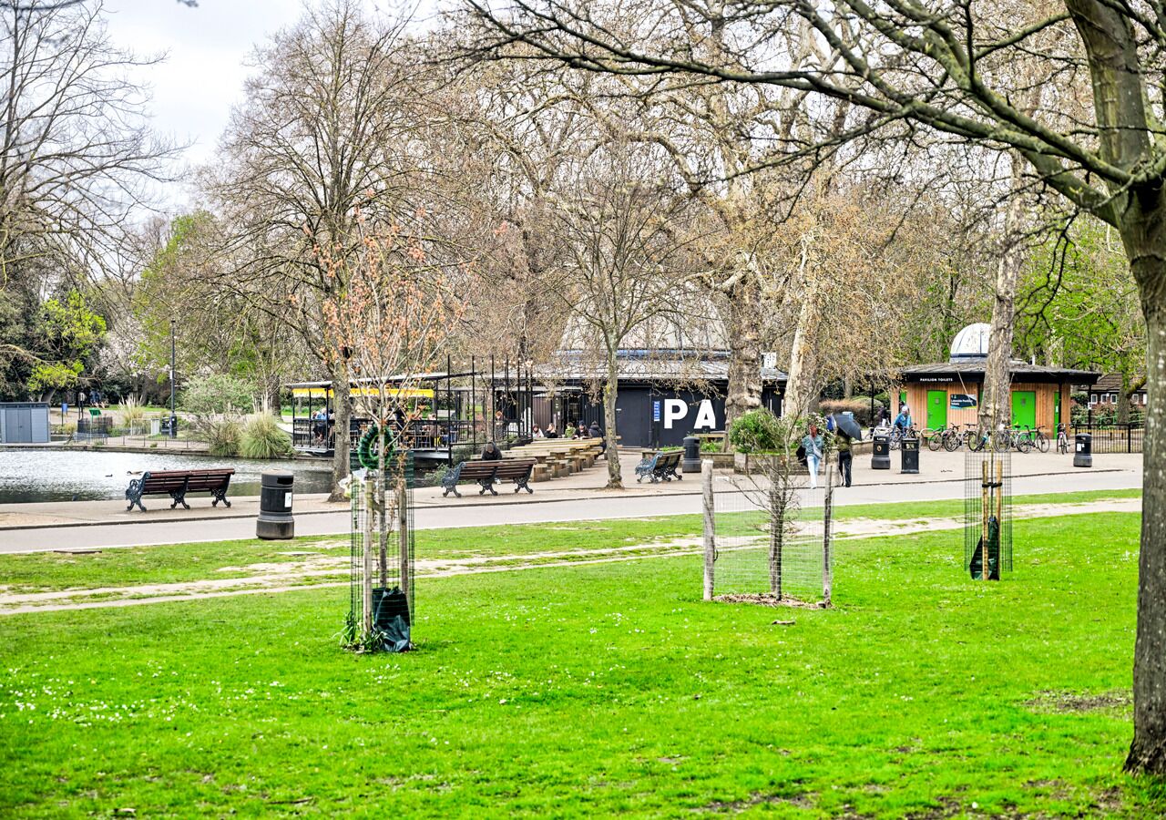 Un parque con bancos, un área de juegos y un edificio con un cartel de PA.