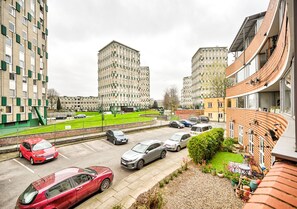 Ein Wohngebiet mit mehrstöckigen Gebäuden, einem Parkplatz mit Autos und einer kleinen Grünfläche.
