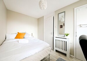 Ein Schlafzimmer mit einem Bett, einem Nachttisch, einem Spiegel und einem Kleiderschrank.