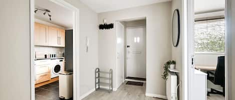 A hallway with a kitchen area, a radiator, and a door leading to another room.