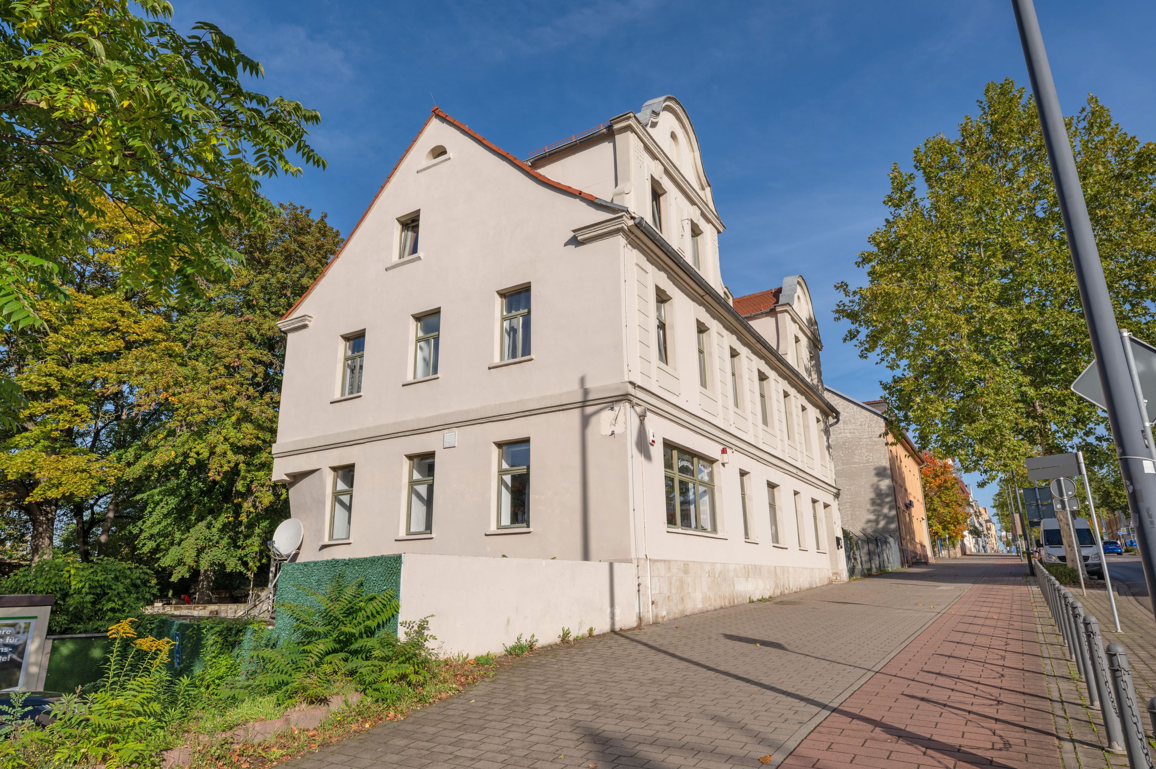 Ein mehrgeschossiges Gebäude mit einer symmetrischen Fassade, großen Fenstern und einem Eckturm.