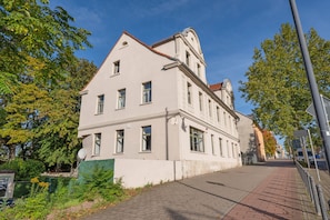 Ein mehrgeschossiges Gebäude mit einer symmetrischen Fassade, großen Fenstern und einem Eckturm.