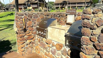 A stone barbecue area with a grill and a sign indicating no smoking.