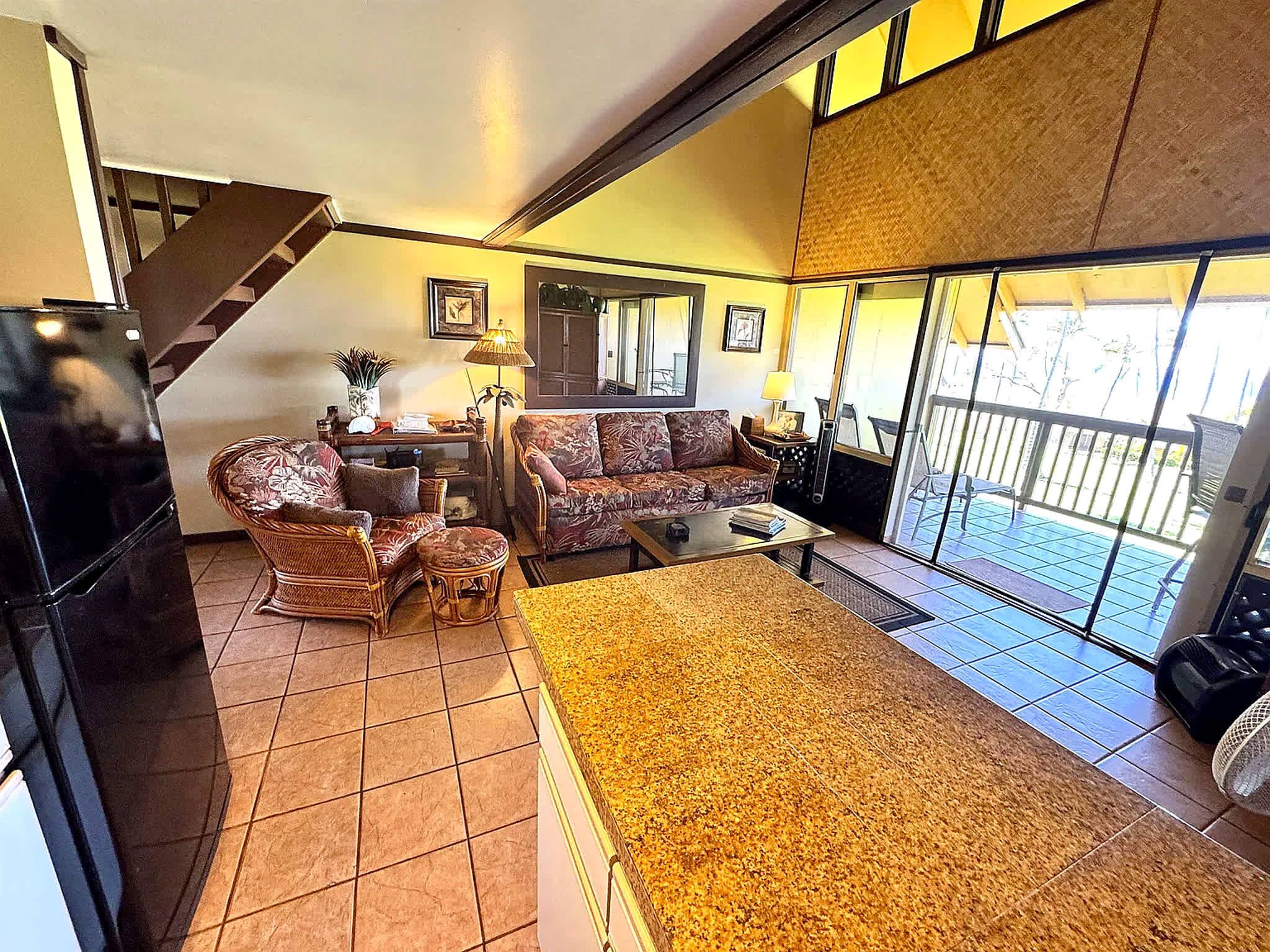 A living room with a sofa, chairs, a coffee table, and a rug. There is a staircase leading to an upper level.