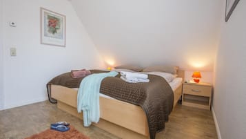 Une chambre à coucher avec un lit, des tables de chevet, une lampe et un tableau encadré au mur.