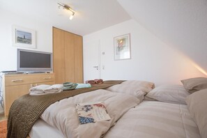 Ein Schlafzimmer mit einem Bett, einem Schreibtisch mit Computer und einem Kleiderschrank.