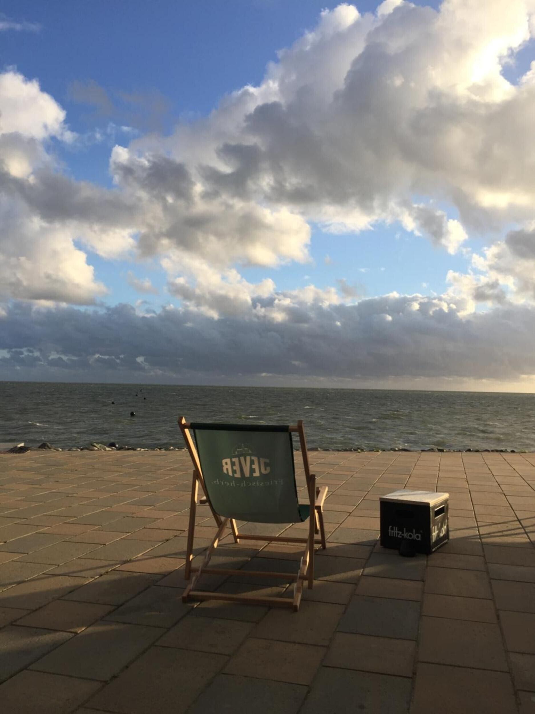 Een strandstoel met 'CERVE' op de rugleuning en een doos met de tekst 'fitzgerald' op de grond.
