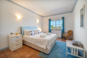 A bedroom with a bed, bedside tables, a chair, and a window with curtains.