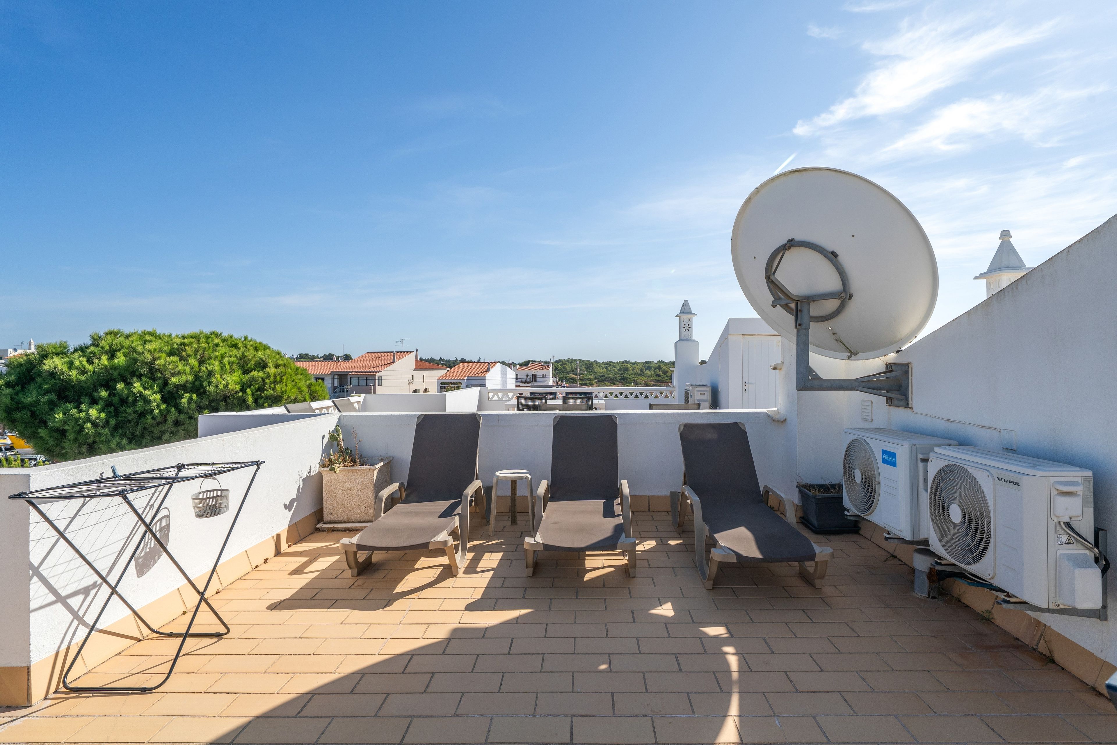 Eine Dachterrasse mit Liegestühlen, einer Satellitenschüssel und einer Klimaanlage.