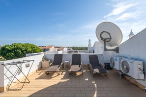 Eine Dachterrasse mit Liegestühlen, einer Satellitenschüssel und einer Klimaanlage.
