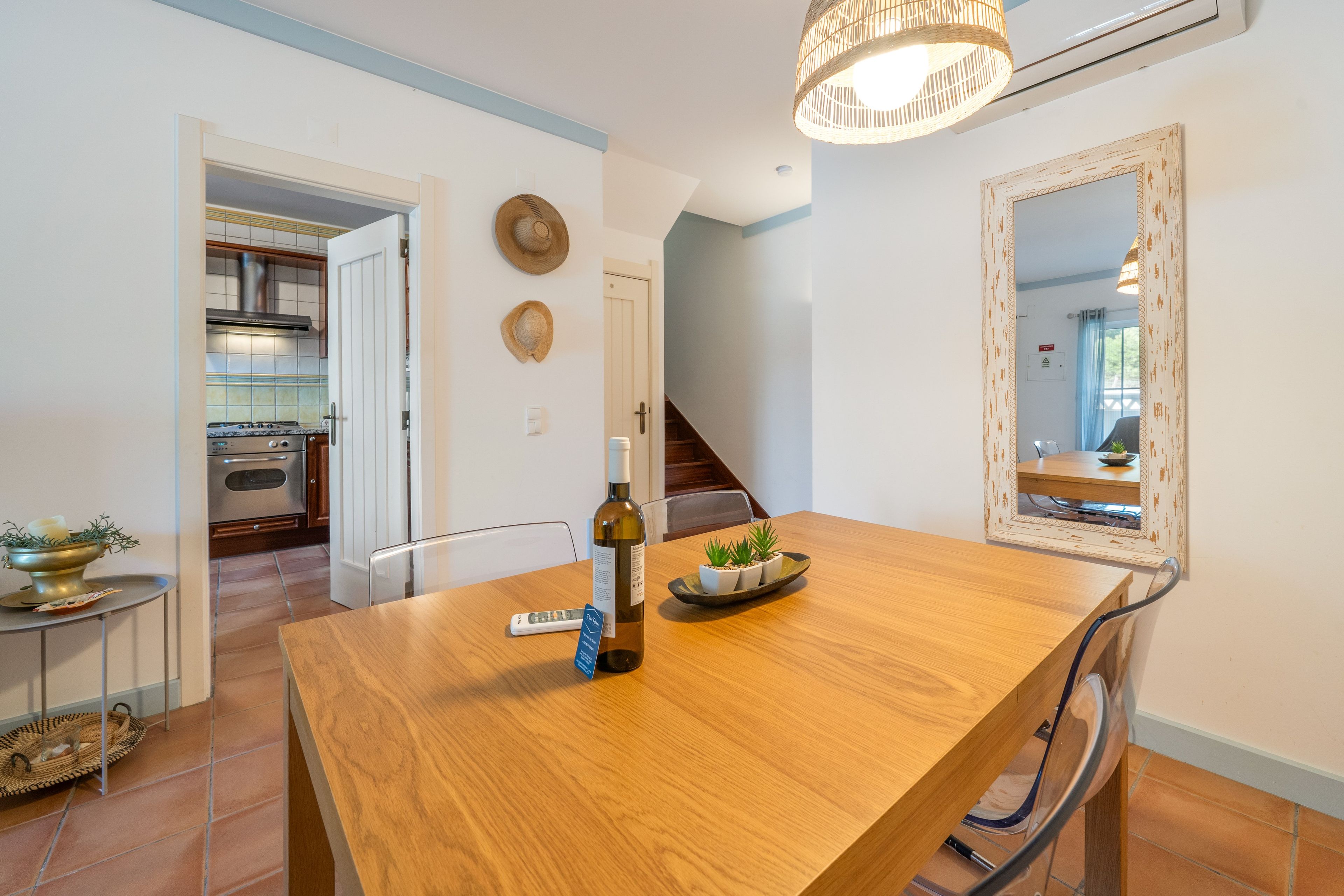 A dining area with a wooden table, a bottle of wine, and a remote control.