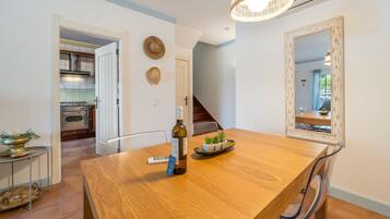 A dining area with a wooden table, a bottle of wine, and a remote control.