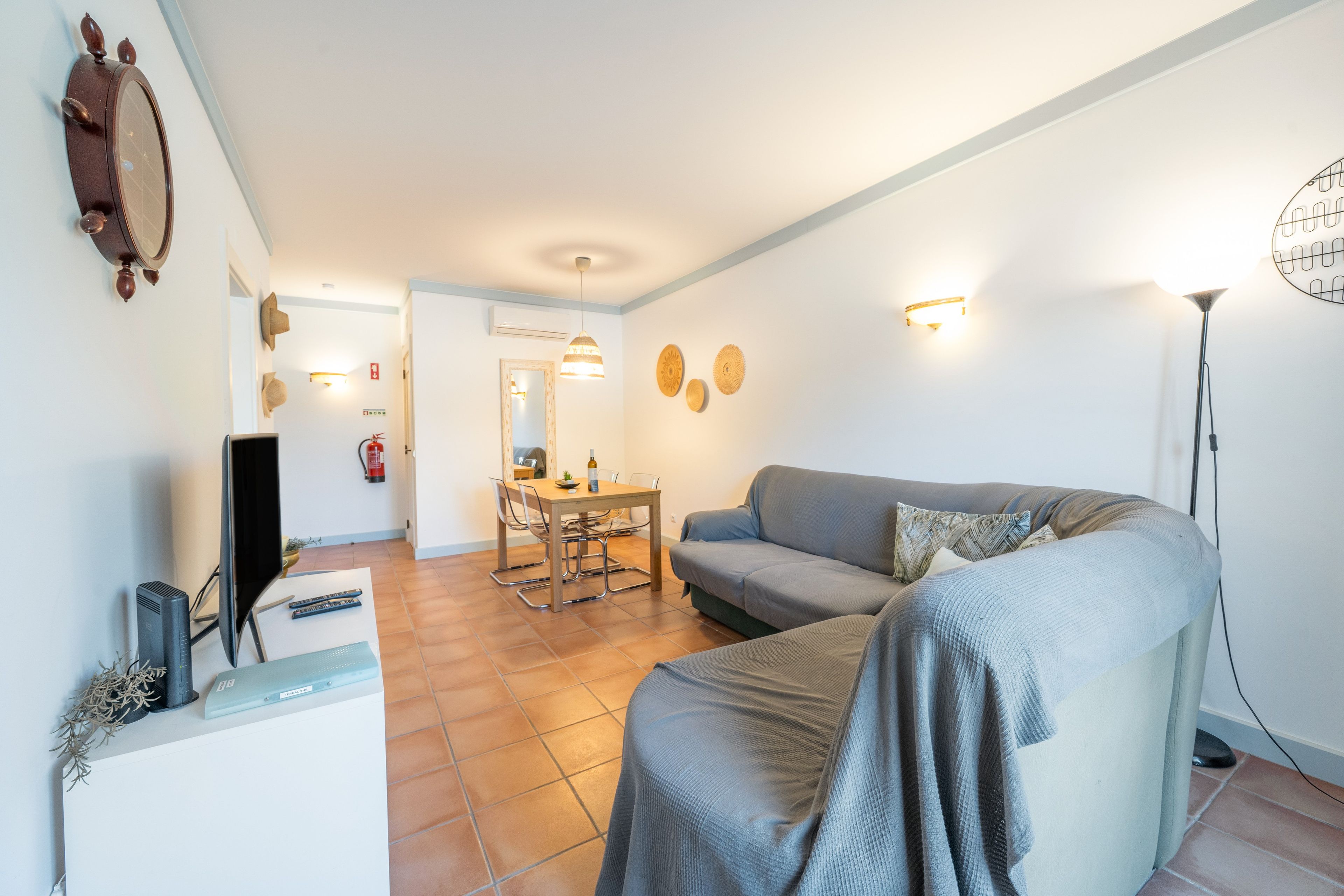 A living room with a sofa, a TV, and a dining area with a table and chairs.