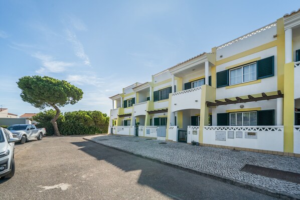 A multi-story building with a paved driveway and parked cars.