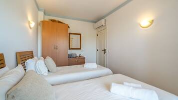 A hotel room with two beds, a wardrobe, a mirror, and a door.