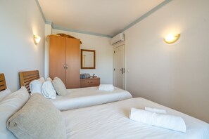 Habitación de hotel con dos camas, un armario, un espejo y una puerta.