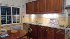 Una cocina con armarios de madera, un fregadero y una mesa de comedor con sillas.