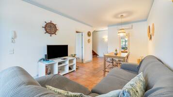 A living room with a television, a dining area with a table and chairs, and a staircase leading to another level.