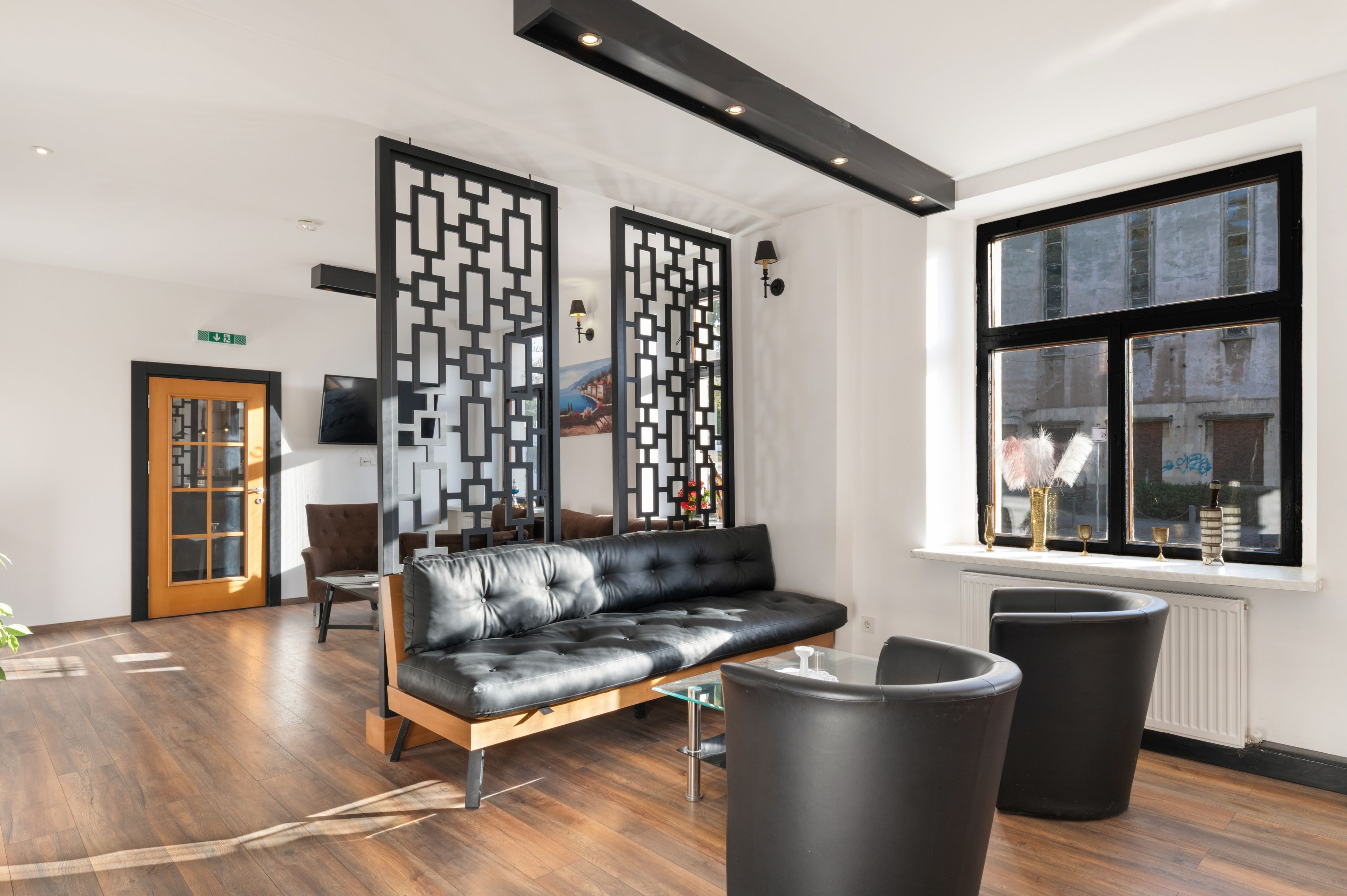 A modern waiting area with a leather sofa, black chairs, and a decorative partition.