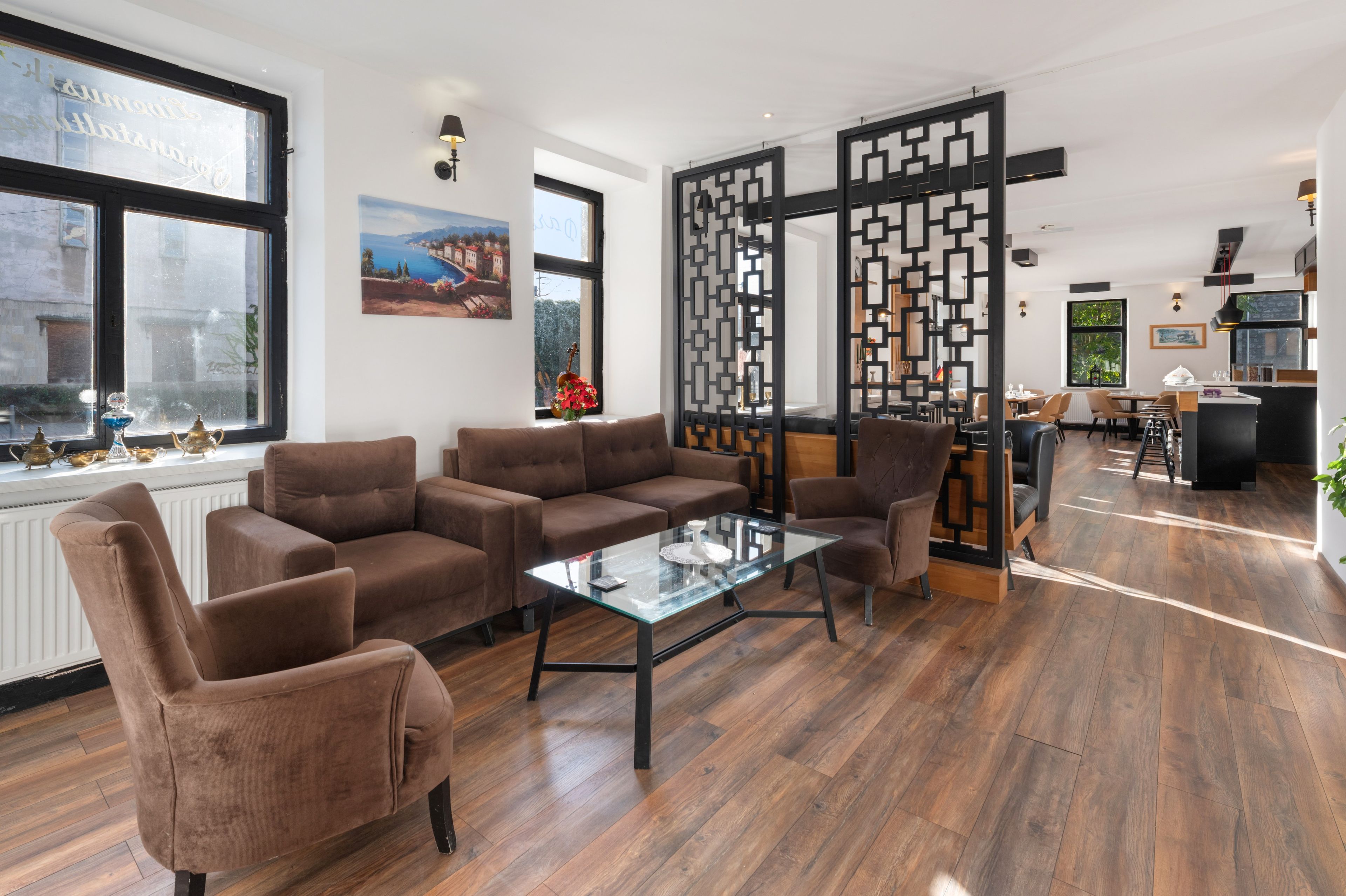 A modern living room with a brown sofa set, a glass coffee table, and a decorative partition.
