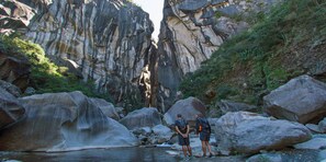 A canyon with large boulders and a small stream.