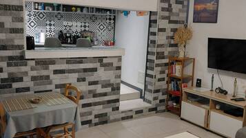 A modern living room with a dining area, a TV, and a kitchen in the background.