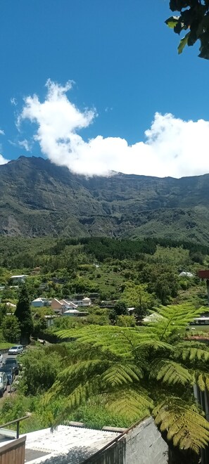A mountainous landscape with a clear sky, a valley with greenery, and a few buildings.