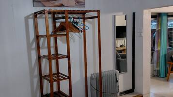A room with a wooden wardrobe, a radiator, a hanging light fixture, and a painting on the wall.