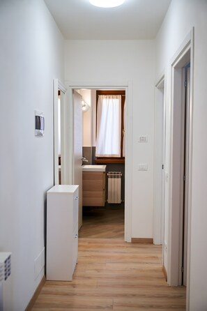 A narrow hallway leading to a bathroom with a shower, a toilet, and a sink. - ‘Dolomis Margherita 4px’ Apartment with Mountain View, Shared Garden and Wi-Fi (Caderzone Terme)