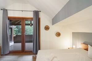Ein Schlafzimmer mit einem großen Bett, einem Holzkopfschild und Blick durch eine Glastür.