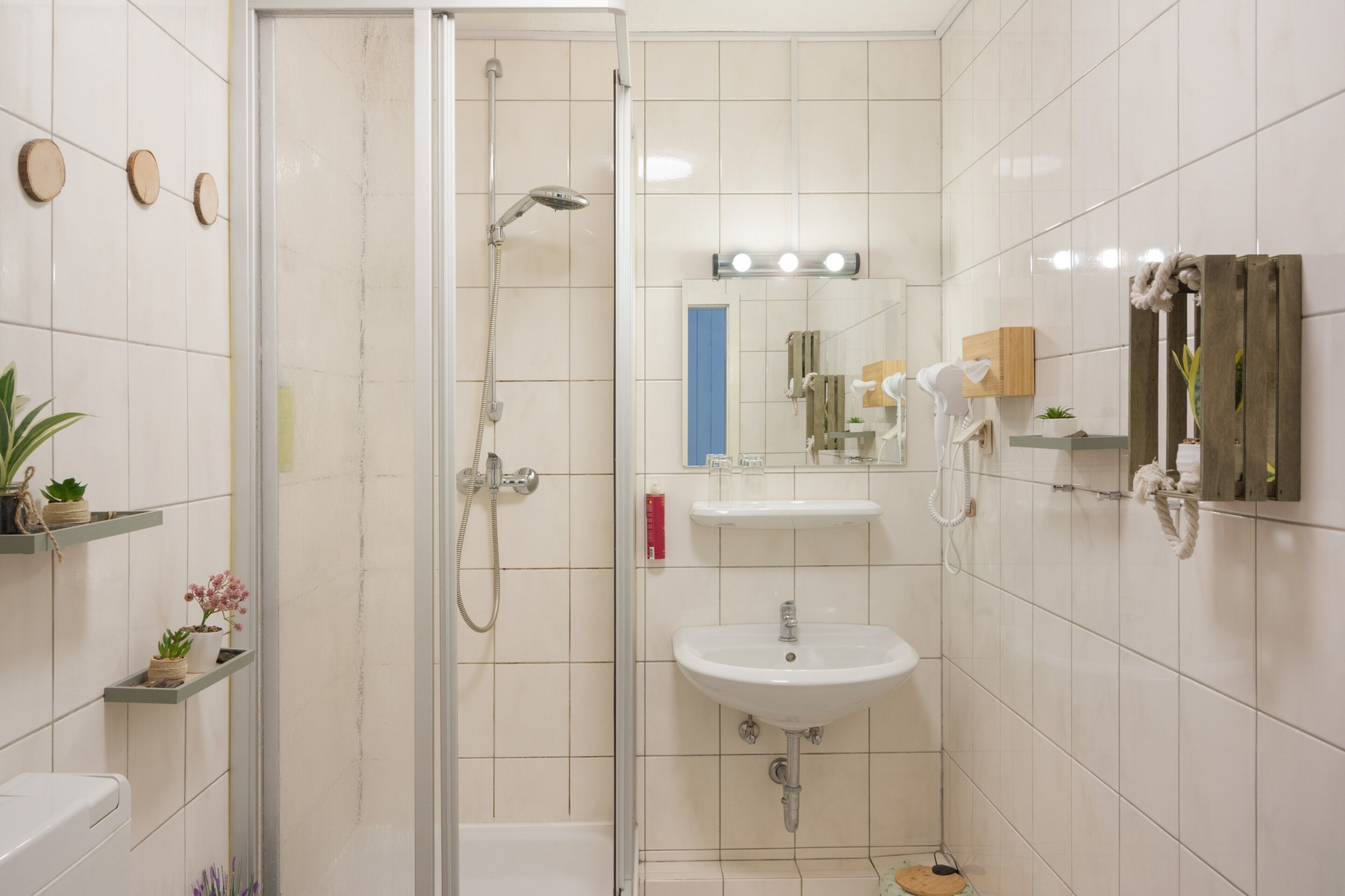 Een badkamer met een douchecabine, een wastafel en een spiegel erboven.