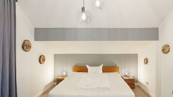 Ein Hotelzimmer mit einem großen Bett, einem Holzkopfstück, Nachttischen mit Lampen und dekorativen Wandbildern.