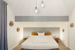 Ein Hotelzimmer mit einem großen Bett, einem Holzkopfstück, Nachttischen mit Lampen und dekorativen Wandbildern.