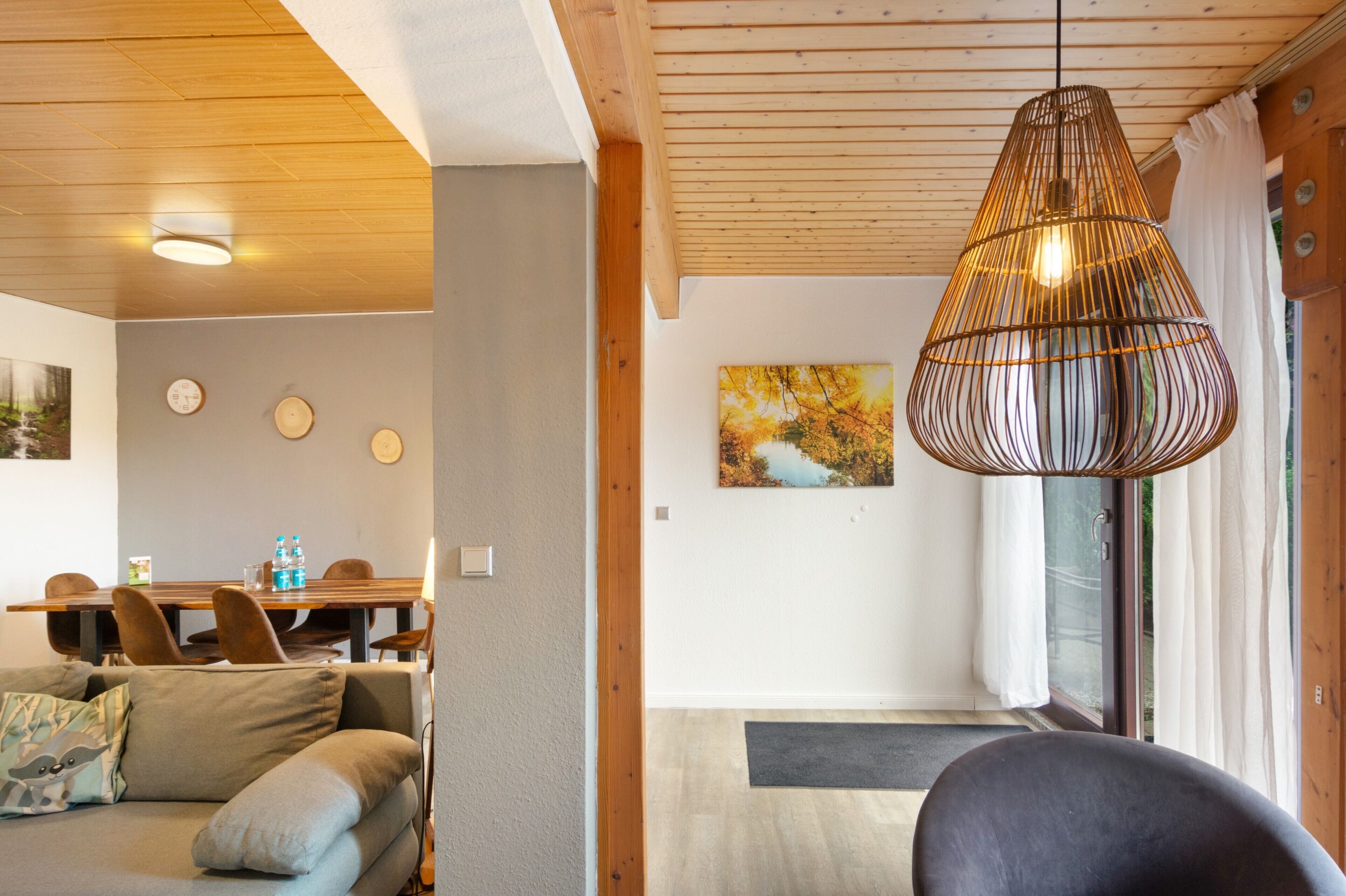 Ein modernes Interieur mit Essbereich, einer Couch, einer Pendelleuchte und einem Gemälde an der Wand.