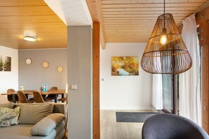A modern interior with a dining area, a sofa, a hanging light fixture, and a painting on the wall.