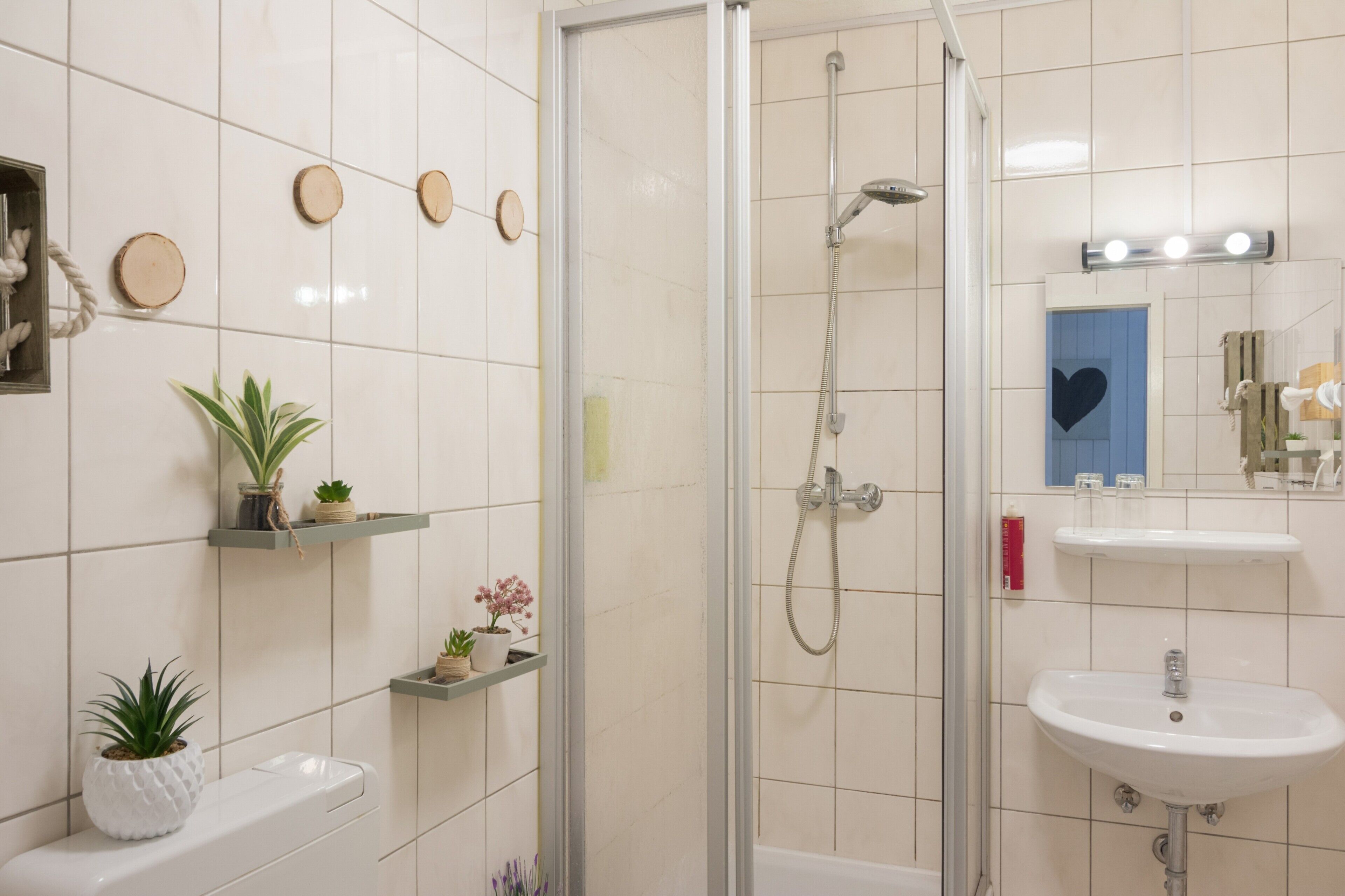 Ein modernes Badezimmer mit einer Duschkabine aus Glas, einem weißen Waschbecken und einem beleuchteten Spiegel.