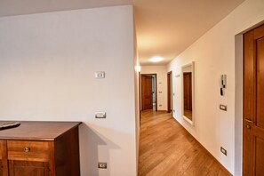 A hallway with wooden flooring, white walls, and doors with light switches. - Dolomis Apartments Rododendro 6 Guests (Caderzone Terme)