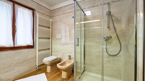 Un baño con ducha de vidrio, inodoro y bidé.