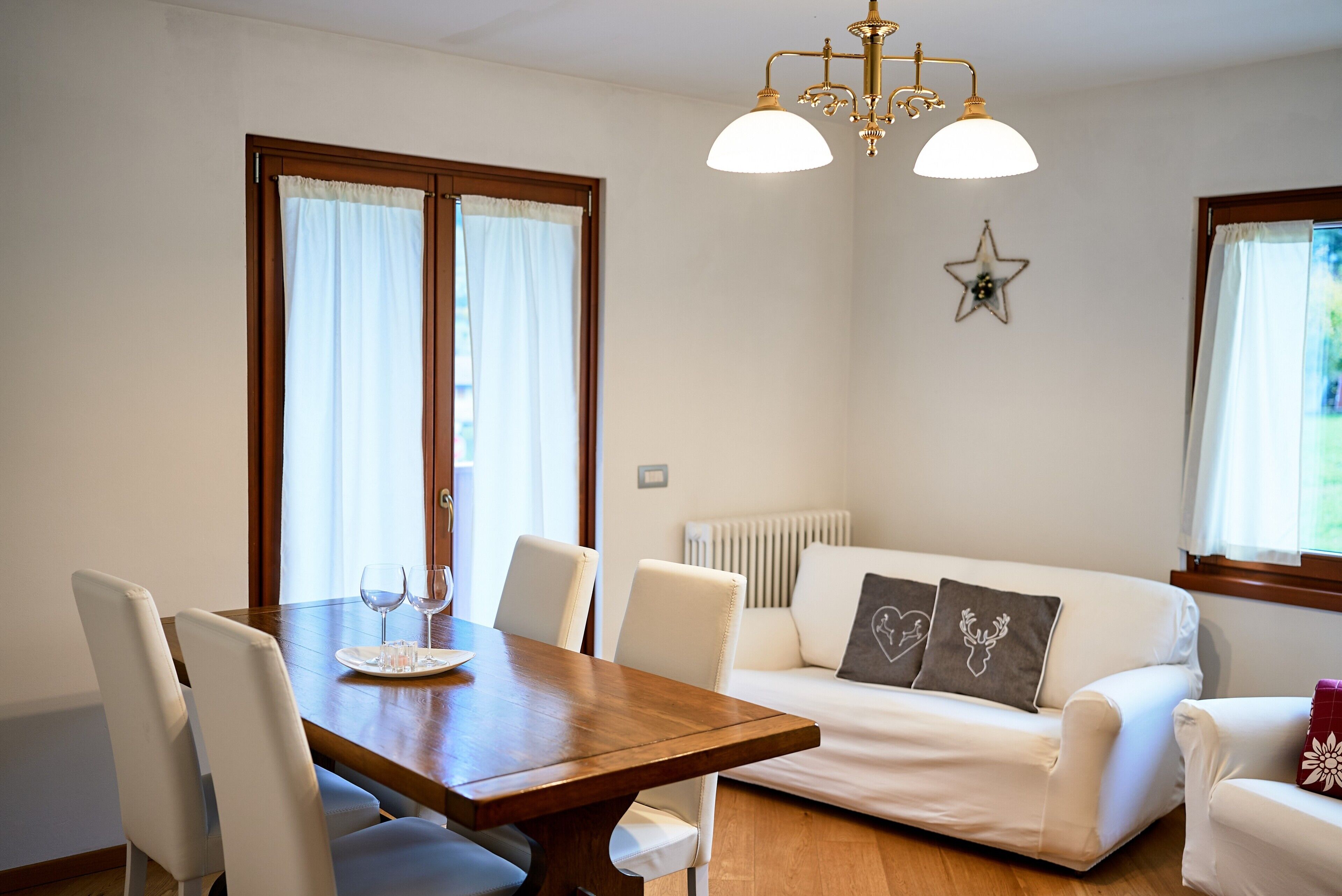 A dining area with a wooden table and chairs, a sofa, and a star-shaped wall decoration.