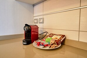 A coffee machine, a red kettle, and a plate with coffee cups and biscotti on a kitchen counter. - Dolomis Apartments Rododendro 6 Guests (Caderzone Terme)