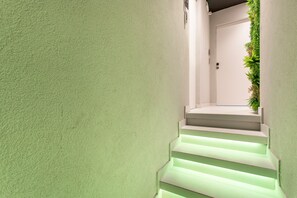 A staircase with illuminated steps leading to a door, surrounded by a textured wall and a vertical garden. - Bed and Breakfast "Camera 102" with Balcony, Wi-Fi and Air Conditioning (Catania)