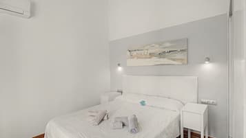 Ein Hotelzimmer mit einem Bett, einem Gemälde, Nachttischen und einer Klimaanlage.