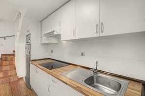 Een moderne keuken met witte kastjes, een roestvrijstalen spoelbak en een houten aanrecht.