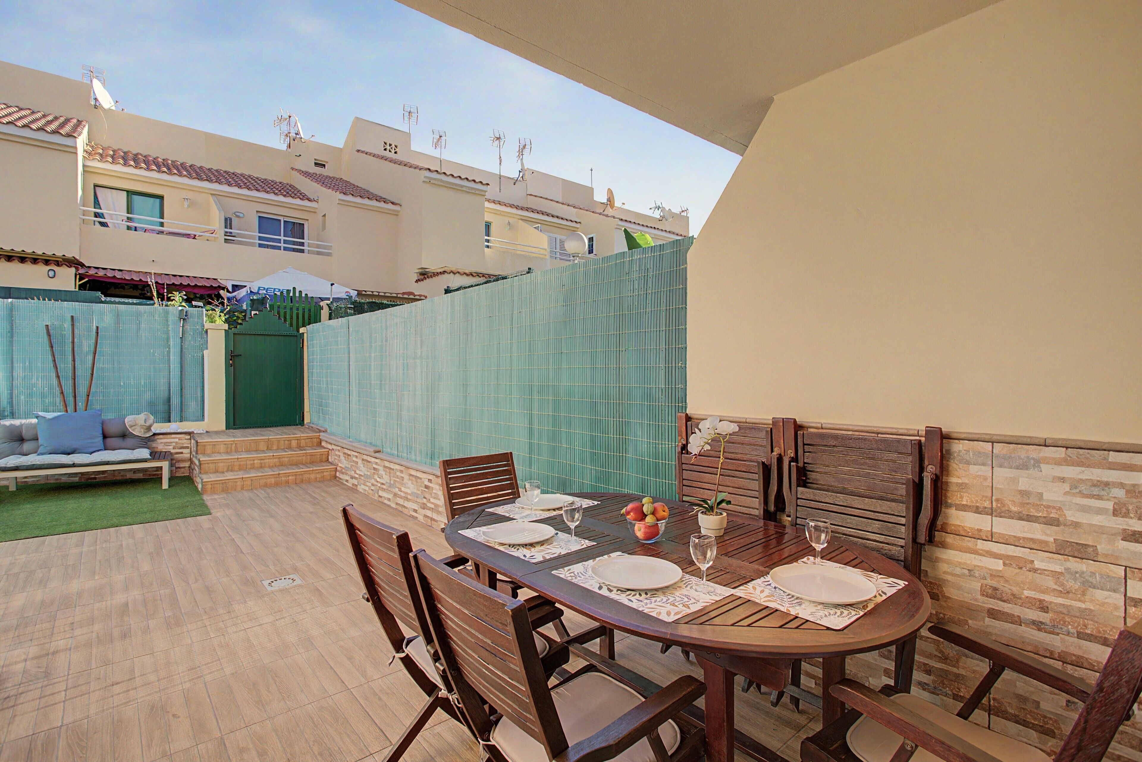 Une terrasse extérieure avec une table à manger pour quatre personnes, entourée de chaises en bois.