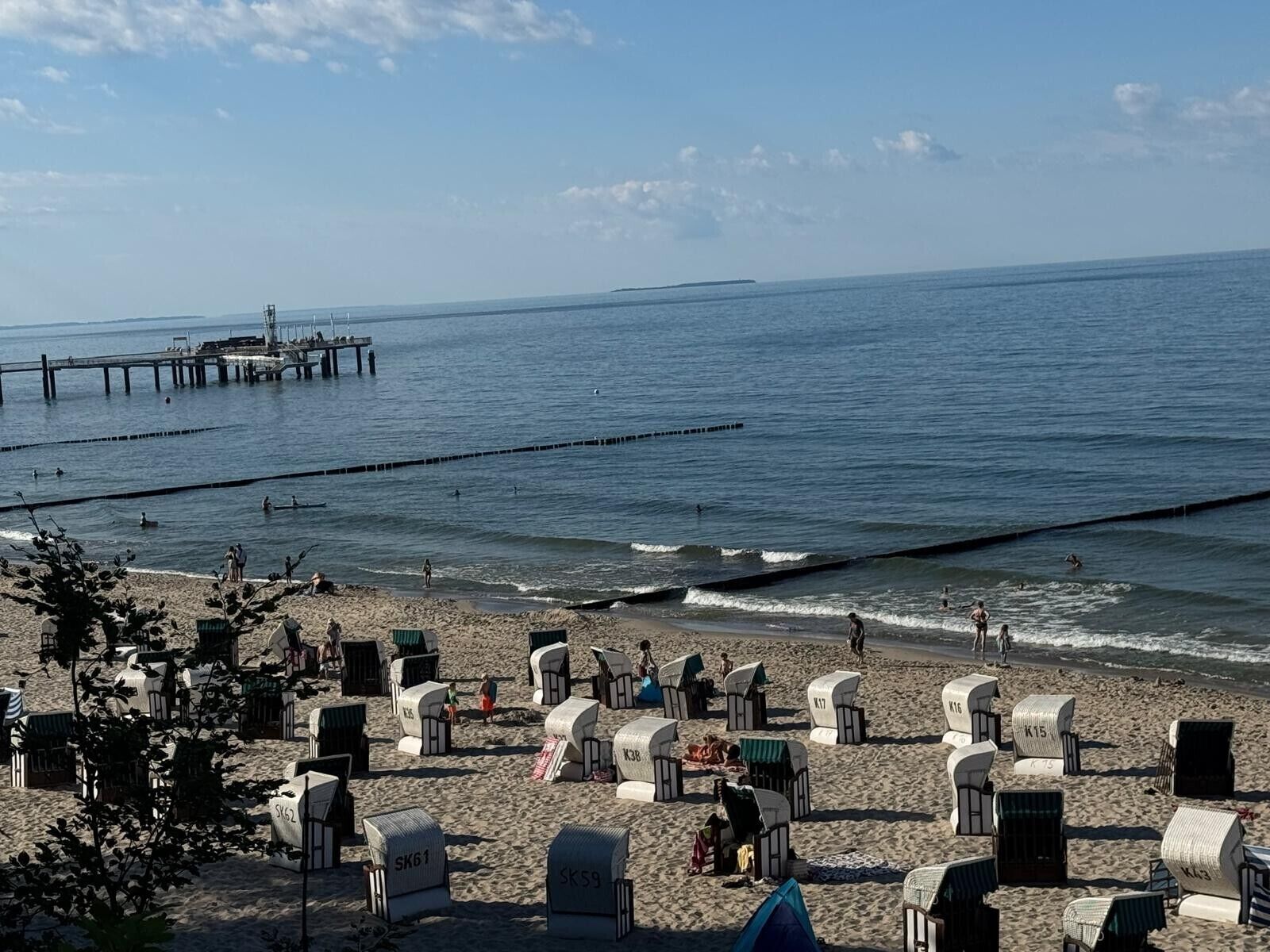 Ein Strand mit Strandkörben und einem Pier im Hintergrund.