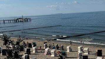 Ein Strand mit Strandkörben und einem Pier im Hintergrund.