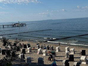 Una playa con cabañas y un muelle al fondo.