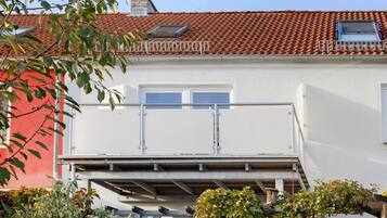 Ein zweistöckiges Gebäude mit rotem Ziegeldach, weißen Wänden und einem Balkon mit Metallgeländern.